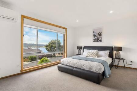 a bedroom with a bed and a large window at Lutana Large house in Hobart