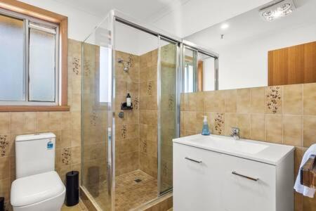 a bathroom with a shower and a toilet and a sink at Lutana Large house in Hobart