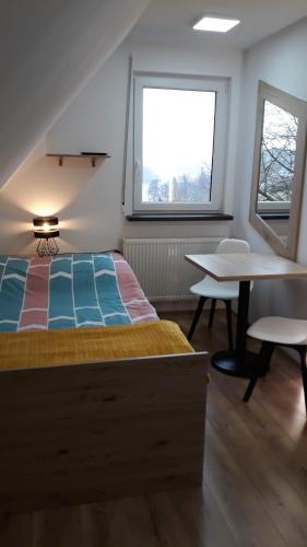 a bedroom with a bed and a table and a window at Leśny Zakątek- Domek Lipa in Parchowo