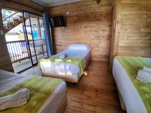 two beds in a room with wooden walls at Cabañas La Moraleja Paraíso Costero in Necoclí