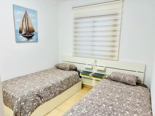 a bedroom with two beds and a window with a sailboat at APARTMENT WITH OCEAN VIEW in Playa del Cura