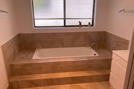 een badkamer met een bad en een raam bij Spacious Modern Home Outstanding Views sleeps 9 in Hobart