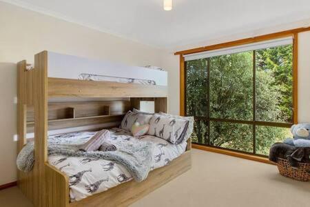 een slaapkamer met een stapelbed en een groot raam bij Spacious Modern Home Outstanding Views sleeps 9 in Hobart