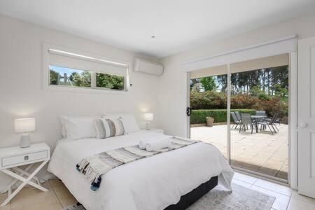 a white bedroom with a bed and a patio at The Rest Retreat Getaway 15 Mins to CBD 3 Bed in Hobart