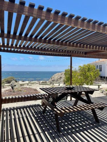 - une table de pique-nique en bois sous un parasol dans l'établissement Cabañas y departamento cerca en primera línea de la playa, à Punta de Choros