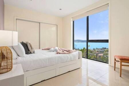 a white bedroom with a large window and a bed at The View Sandy Bay 5 bedroom in Hobart