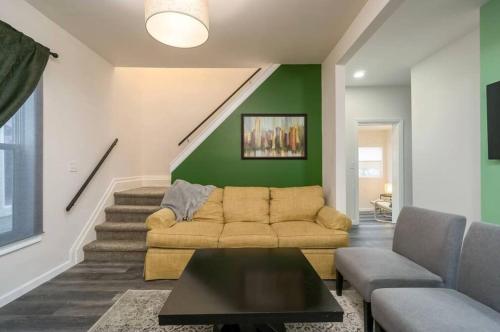 a living room with a couch and a staircase at Housepitality - The Mint Julep House in Columbus