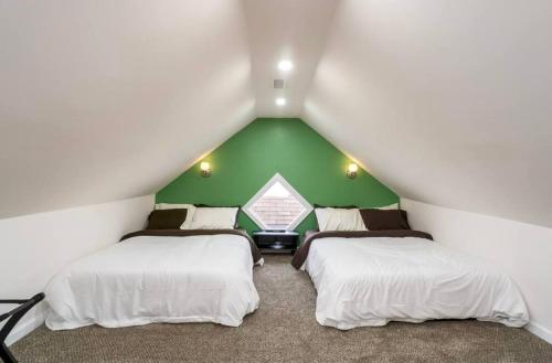 two beds in a room with a green wall at Housepitality - The Mint Julep House in Columbus