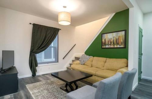 a living room with a couch and a green wall at Housepitality - The Mint Julep House in Columbus
