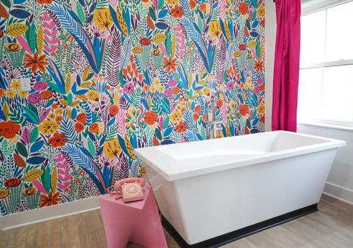 a bathroom with a white tub and a floral wallpaper at Ice Cream Retreat at Casa Kumwesu in Bellmead