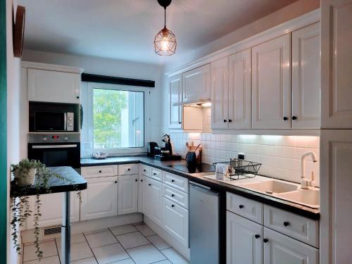 une cuisine avec des armoires blanches, un évier et une fenêtre dans l'établissement Cosy Case between Disney and Paris, à Champs-sur-Marne