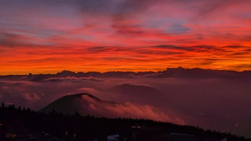 a sunset over the mountains with a layer of clouds at Chamrousse 1750 Roche Béranger 50m2 4-6pers Vue panoramique in Chamrousse