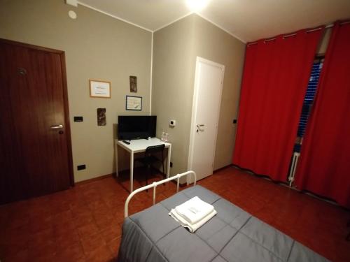 a room with a bed and a desk and a red curtain at EasyRoom Schio in Schio