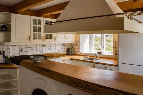 a kitchen with white cabinets and a large hood at The Mill House - Saeby Watermill in Sæby