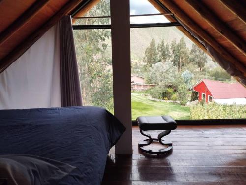 - une chambre avec un lit et un tabouret devant une fenêtre dans l'établissement Chullpa's House, à Urubamba