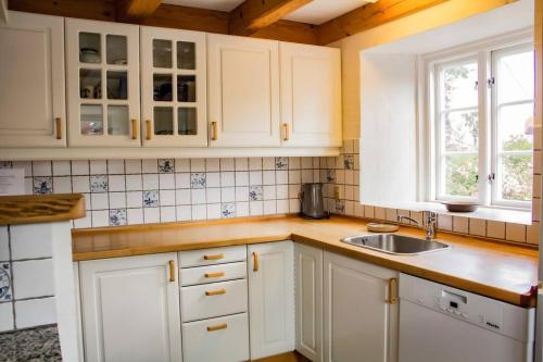 a kitchen with white cabinets and a sink at The Mill House - Saeby Watermill in Sæby