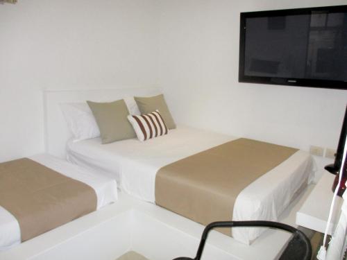 a bedroom with two beds and a flat screen tv at Rincón del mar Veleros Hotel in San Onofre