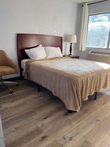 ein Schlafzimmer mit einem Bett, einem Stuhl und einem Fenster in der Unterkunft Travelers Inn Topeka in Topeka