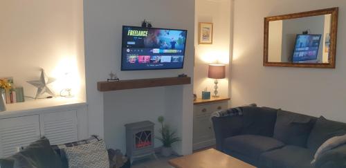 a living room with a couch and a television on a wall at Eden Rose Cottage in Morecambe