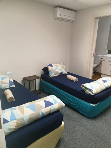 a room with two beds and a table and a bedskirts at Backpackers Central Hamilton in Hamilton