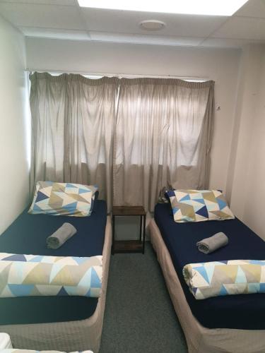 two beds in a small room with a window at Backpackers Central Hamilton in Hamilton