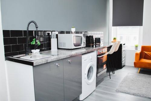 a kitchen with a washing machine and a microwave at Vibrant Studio Close to Anfield Stadium in Liverpool