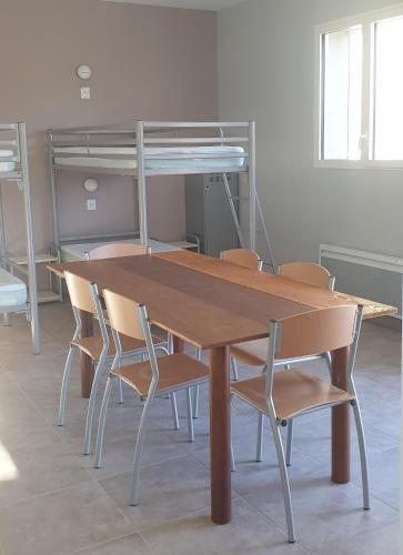 Rambaud的住宿－Rambaud Refuge Pèlerins，一张带椅子的木桌和一张双层床。