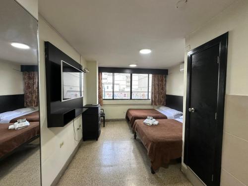 una camera d'albergo con due letti e una televisione di Residencia Terreros a Guayaquil