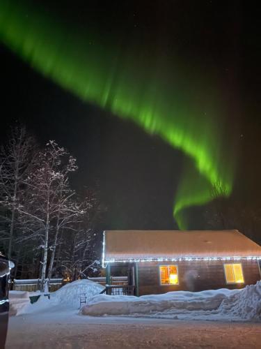 a building with the aurora above it at night at Chinook Wind Cabins in Talkeetna