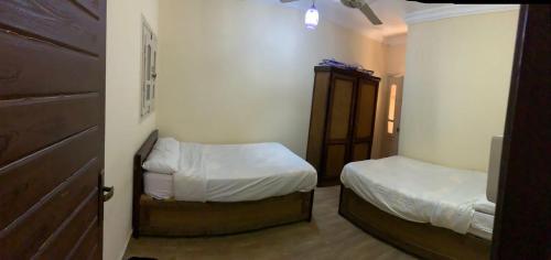 Habitación pequeña con 2 camas y armario. en Almanara Hotel Marsa Matrouh, en Marsa Matruh