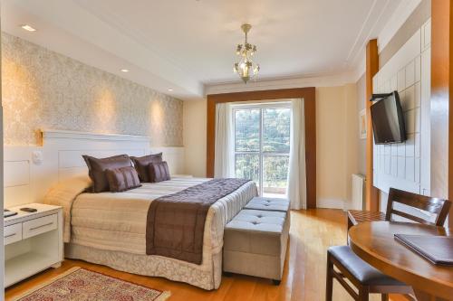 a bedroom with a bed and a desk and a television at Carballo Hotel & Spa in Campos do Jordão