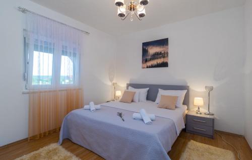 a white bedroom with two beds and a chandelier at Apartment Marendić in Obrovac Sinjski