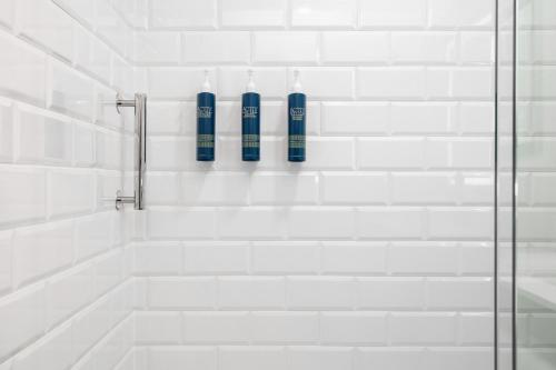 a bathroom with a shower with two blue bottles at Four Points by Sheraton Kelowna Airport in Kelowna