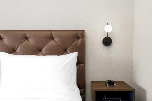 a bed with a white pillow and a side table at Four Points by Sheraton Kelowna Airport in Kelowna