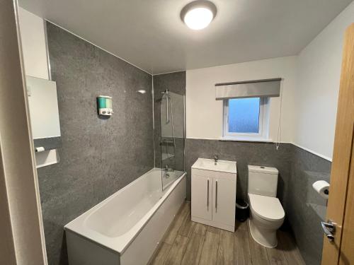 a bathroom with a toilet and a tub and a sink at Inchcailloch Townhouse, Loch Lomond in Bonhill