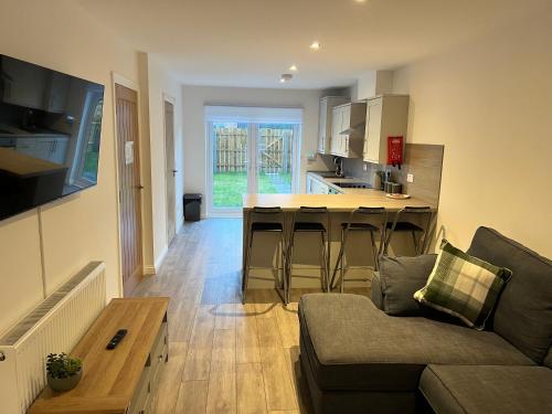 a living room with a couch and a kitchen at Inchcailloch Townhouse, Loch Lomond in Bonhill