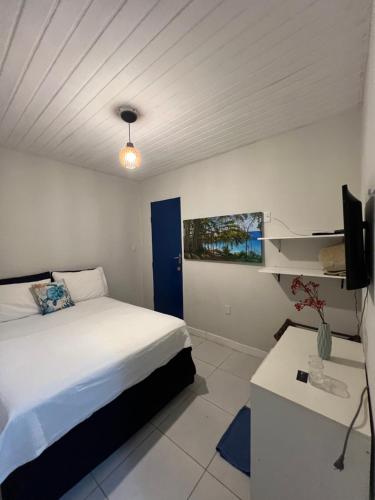 Schlafzimmer mit einem Bett, einem Schreibtisch und einem TV in der Unterkunft Coral azul Noronha in Fernando de Noronha