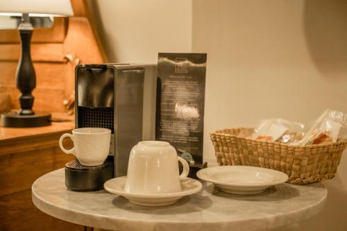 a table with two cups and plates and a coffee maker at Hotel Boutique Naura Centro in Oaxaca City