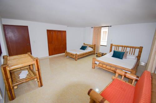 a living room with two beds and a chair at Hotel Toledo Plaza in Armenia