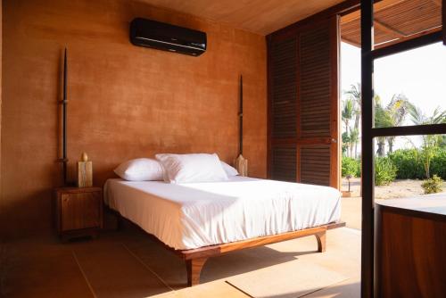 a bedroom with a bed with white pillows at Mazul Puerto Escondido in Tlachicón