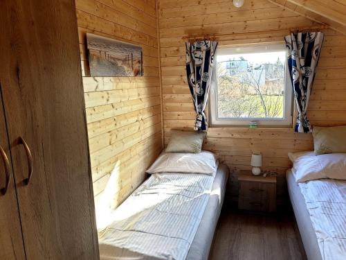 2 Betten in einem kleinen Zimmer mit Fenster in der Unterkunft Baltic Summer - ośrodek dla rodzin z dziećmi in Rewa