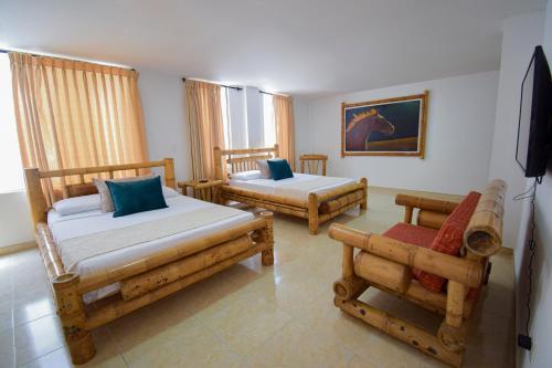 a bedroom with two beds and two chairs at Hotel Toledo Plaza in Armenia