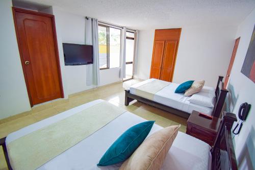 a hotel room with two beds and a television at Hotel Toledo Plaza in Armenia