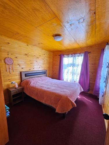 ein Schlafzimmer mit einem Bett in einer Holzhütte in der Unterkunft Casa familiar en Isla Lemuy in Puqueldón