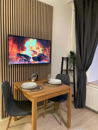 a wooden table with chairs and a tv on a wall at Residenz am Kurpark - Ferienwohnungen in zentraler Lage I Privatparkplatz in Bad Rothenfelde
