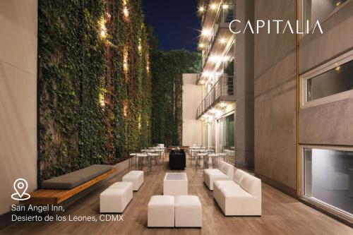 un restaurante con sillas blancas y una pared verde en Capitalia - ApartHotel - San Angel Inn, en Ciudad de México