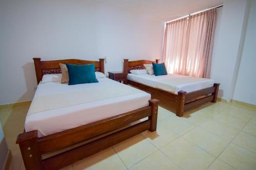 a bedroom with two beds and a window at Hotel Toledo Plaza in Armenia
