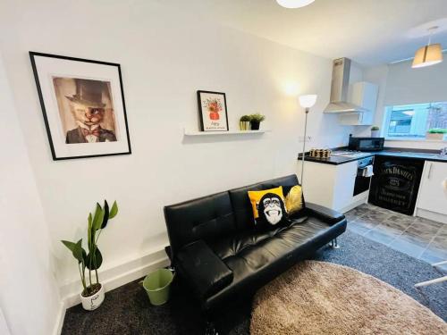 a living room with a black leather couch and a kitchen at Artistic 1Bed Apt near the City Centre in Liverpool