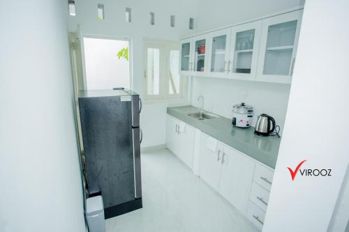 uma cozinha com armários brancos e um frigorífico de aço inoxidável em Virooz Residence Rathmalana 2 Bedroom Apartment em Borupane