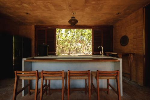 a kitchen with three chairs at a counter with a sink at Mazul Puerto Escondido in Tlachicón